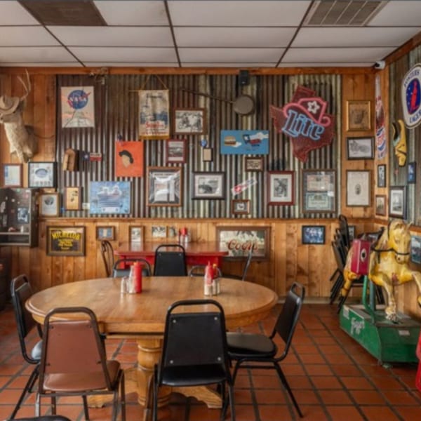 Miller's Cafe interior with wooden tables, chairs, and walls adorned with various framed pictures and signs.
