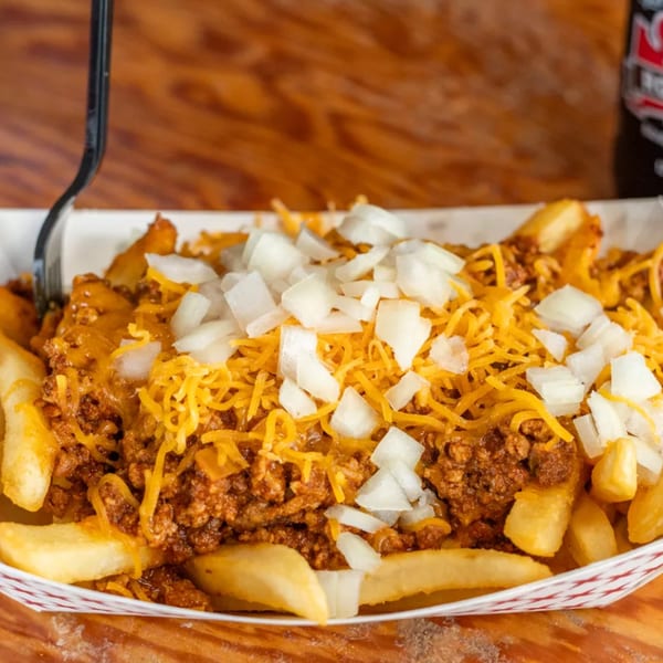 Miller's Cafe chili cheese fries with diced onions in a paper tray.